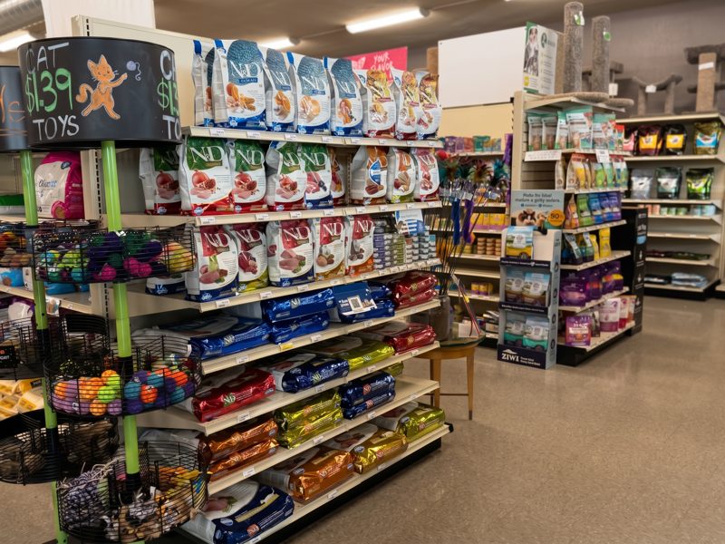 An endcap of dog treats and toys near the front of the store